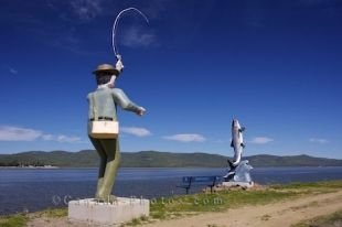 Statues of a fisherman and an Atlantic Salmon along the river bank in Campbellton, New Brunswick overlook the Restigouche River.